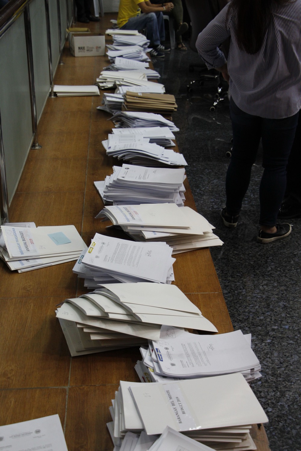 Piles of paper construction documents spread along a long table